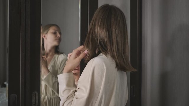 young woman smells perfume and sprays on neck