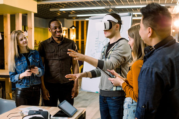 Business team of young multiethnical people presenting new project to a client on a virtual reality simulator. Young Caucasian man the client with VR glasses.