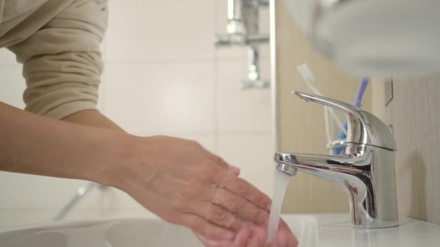 Woman is opening tap and washing face
