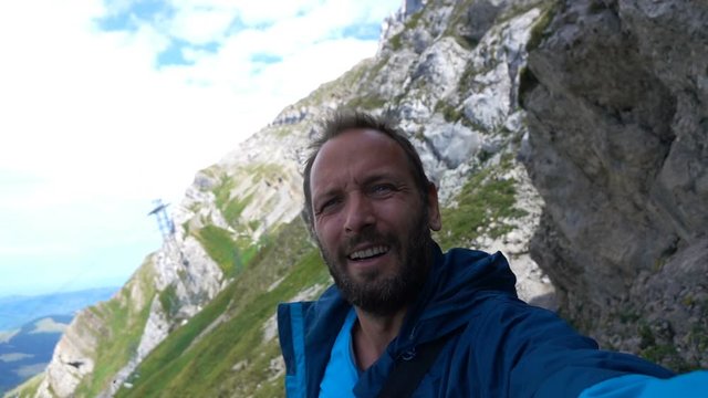 Young, happy man taking selfie photo in mountains, super slow motion