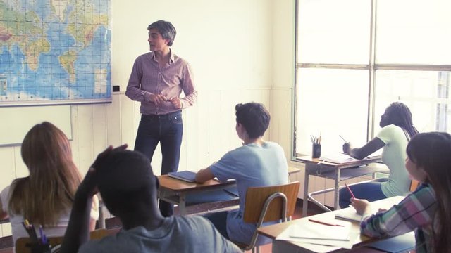 Teacher explaining geography to his students in the classroom, sunlight coming from outside