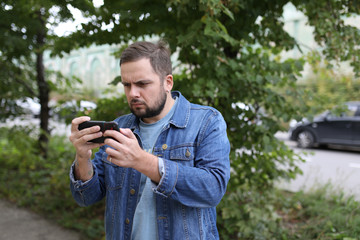 man carefully and thoughtfully looks at his smartphone