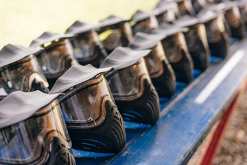 Protective black helmets for paintball lie on a wooden shelf ready for a new game, drying the helmet outside after washing, selective focus in the foreground