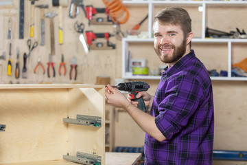 Young bearded man working at the furniture factory