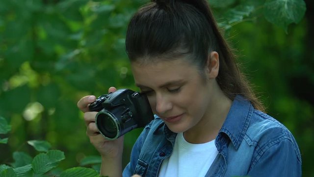 Young woman taking pictures of trees, exploring plant species, admiring nature