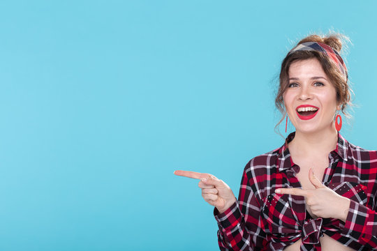 Positive beautiful young woman in a plaid vintage shirt looking at the camera and smiling posing on a blue background with copyspace