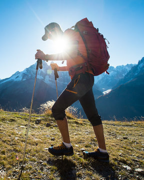 A hiker in the mountains with the sun shining over the mountains.