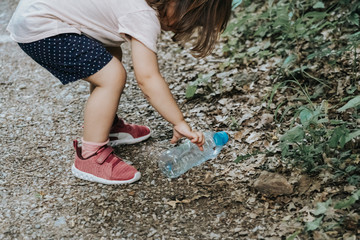 girl collecting plastic in the field, with her mother and grandmother
