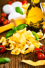 Ribbon Pasta Noodles Uncooked on Wooden Background. Selective focus.