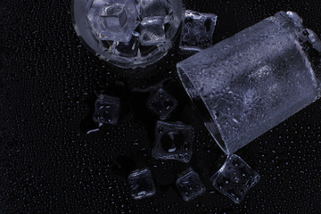 A foggy inverted glass and ice lie on a black background, cold condensate.