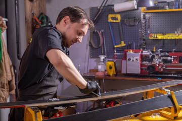Fototapeta na wymiar A man repairman in workshop ski service repairing the ski