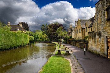 Ducks swimming on River Windrush in sunshine after a rain storm in Bourton-on-the-water Cotswold England