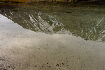 Scene view of snow-capped mountains reflected on water near lagoon shore in Patagonia, Esquel, Argentina