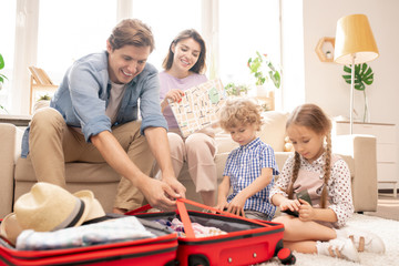 Young couple and two little kids preparing things before travel