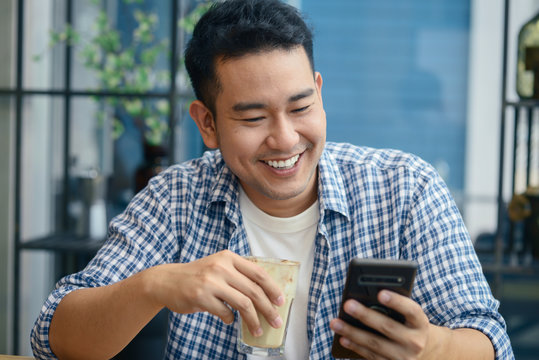 Smart Asian man using smartphone in cafe, lifestyle concept.