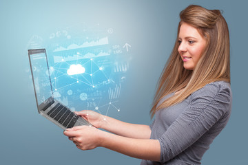 Woman holding laptop projecting cloud based system symbols and informations