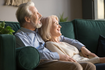 Elder happy smiling retired family couple relaxing on couch.