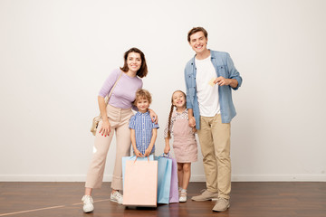 Joyful young parents and their two kids with paperbags looking at you © pressmaster