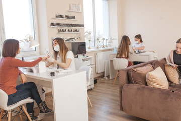 Manicurist making a manicure in the salon. Master servising her client. Nails care procedure.