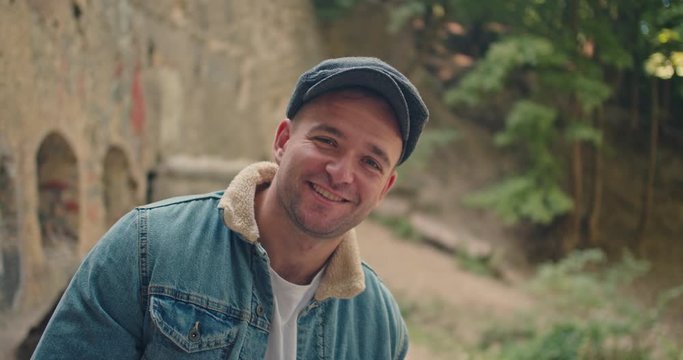 Handsome man in blue jeans jacket and white shirt, stylish hat looking around right and left . Peacy blinders. Waiting for something , Underground location, Camera rotation 