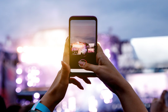 A Girl Is Taking Pictures Of A Street Concert On The Phone.