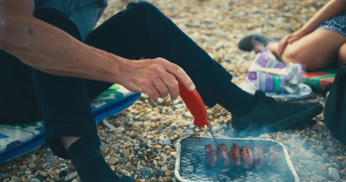 Senior man on beach using meat thermometer