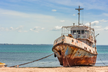 An old weathered and rusting ship/fishing boat anchored on the beach of the Island of Mozambique (Ilha de Mocambique) on a sunny day. Nampula Province, Mozambique, Africa