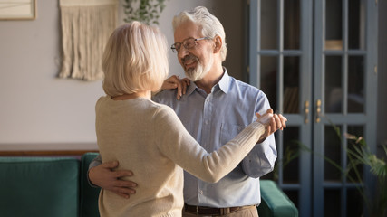 Elderly couple enjoy time together dancing at home
