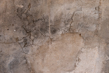 Background in the form of a plastered surface of gray color with many cracks of different shapes and sizes