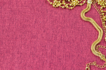 Background in the form of a chain-snake and beads of golden color for Christmas decorations on a burgundy background, top view