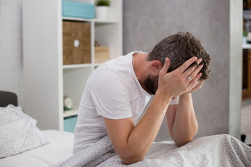 Man waking up in his bedroom and rubbing his eyes.