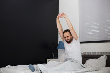 Man waking up in his bedroom and stretching.