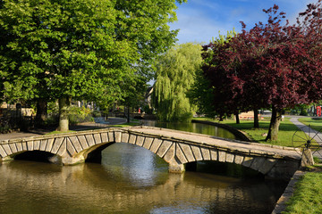 Bridge over the River Windrush in morning sun with trees in Bourton-on-the-Water village in the Cotswolds England