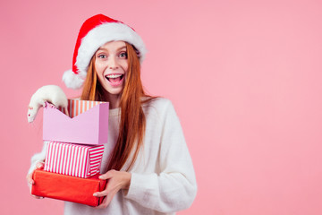 amazed and surprised redhaired ginger girl in red santa hat holding a bunch of gifts boxes and cute rat in studio gray background.two thousand and twentieth year symbol