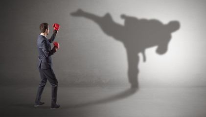 Fototapeta premium Businessman fighting with his strong karate man shadow