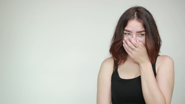 beautiful girl in black tank top over isolated white background shows emotions