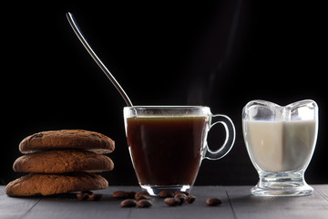 cup of coffee with milk and cookies on a black background