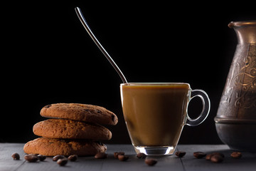 glass of coffee with oatmeal cookies on a black background