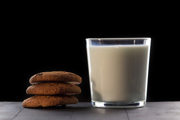 Milk with cookies on a black background