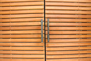 Part of brown wood doors and black metal handle. Wood doors modern style