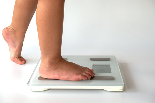 side view close-up of kid feet on digital body fat analyzer scales on white background. fat burn and good health concept.