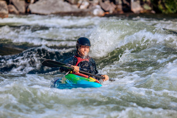 Fototapeta na wymiar Guy in kayak sails mountain river. Whitewater kayaking, extreme sport rafting