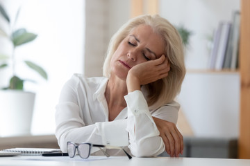 Exhausted senior businesswoman fall asleep at workplace