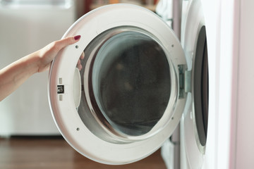 Woman opens the door of the washing machine.