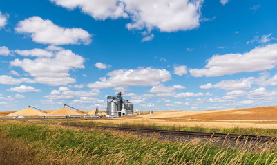 Fototapeta premium Landscape of Three Huge, Amazing Pyramids-of-Grain at the Harvest Grain Processing and Transportation Site near the Town of Oakesdale WA