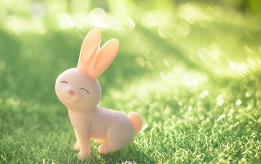 Cute rabbit doll stand alone on the natural green background, Morning sunshine, Selective focus,Vintage Style, Easter Festival.