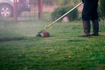 Man in rubber boots mows grass.