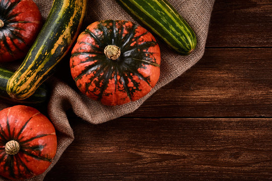 Flat lay Photo Orange pumpkins and green zucchini on sacks of jute. Old wooden background
