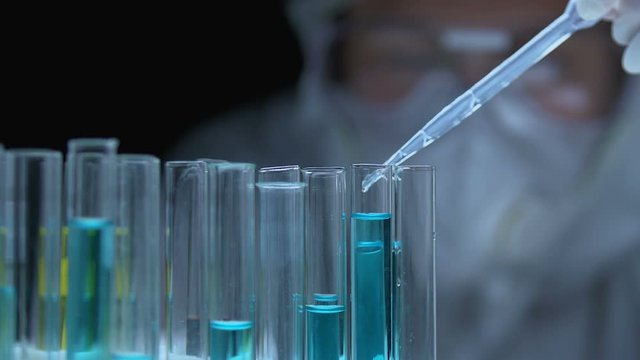 Researcher dripping chemical liquid into tube, analyzing substance properties