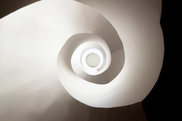 Photograph of a white spiral staircase, which creates the shape of a shell.
